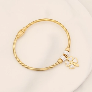 Detail of gold snake chain bracelet with white clover pendant and crystal beads