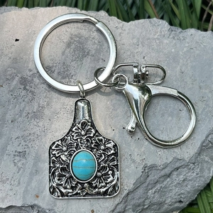 Detail of silver western key ring with turquoise stone and carved floral tag on stone