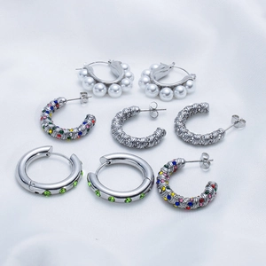 Retro stainless steel hoop earrings set with zircon and pearls on white silk background