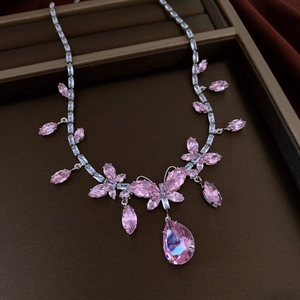 Makroaufnahme von rosa Zirkon-Schmetterlingshalskette und Wassertropfen-Ohrringen im Etui