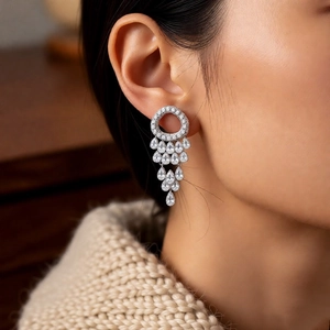 Close-up of silver tassel earrings with zircon water drops worn by a model in soft light