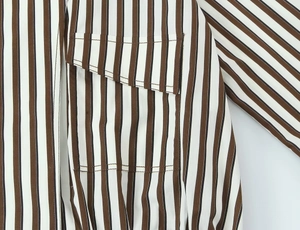 Détail de rayures verticales marron et blanc sur une chemise tissée avec poche cousue