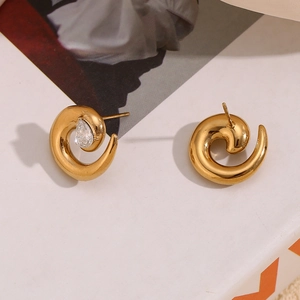 Macro detail of gold snake-shaped spiral earrings with a sparkling teardrop zircon