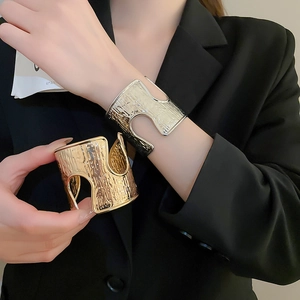 Macro detail of wide metallic cuff with irregular hammered texture on model