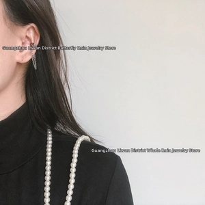 Macro view of silver tone chain ear cuff with double tassel drop on female model ear