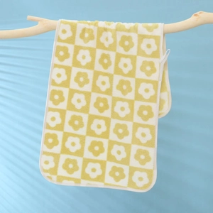 Soft coral fleece towel with checkered flower pattern hanging on a wooden branch