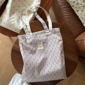 Detail of lavender floral cotton tote bag with vintage fabric label and sturdy cream handles