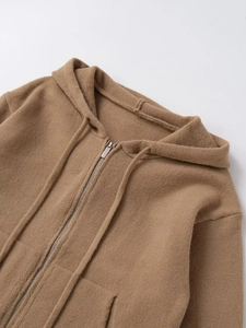 Detail of tan drawstring hoodie showing premium textured knit fabric and metal zipper close-up