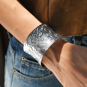 Detail of bohemian wide silver cuff bracelet with intricate floral relief patterns