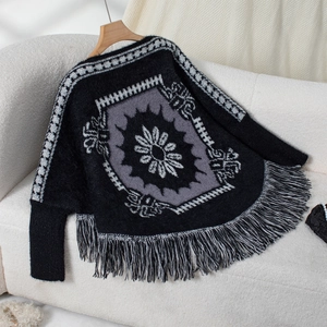 Detailed view of a black and grey knit poncho with geometric patterns and fringe tassels