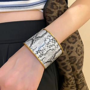 Close-up of a wide gold cuff bracelet featuring a stylish black and white snakeskin pattern
