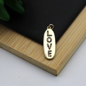 Macro detail of gold 18K plated oval pendant with colorful zircon stones spelling LOVE