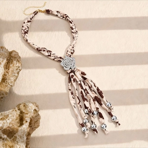 Détail d'un collier de pull en tissu bohème avec rose en strass et perles argentées