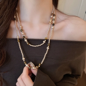 Dettaglio della collana di perle occhio di tigre a strati su una modella con texture