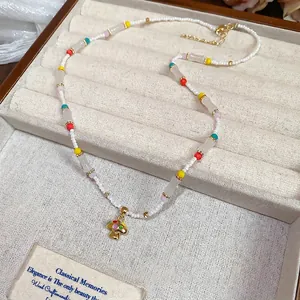 Colorful beaded necklace with gold mushroom pendant displayed in a beige jewelry gift box