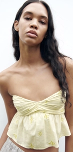Détail du haut bustier jaune clair avec broderie délicate et tissu en coton plissé