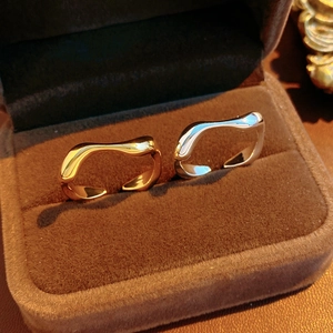 Close-up of gold and silver irregular wavy rings displayed in a luxury brown velvet box
