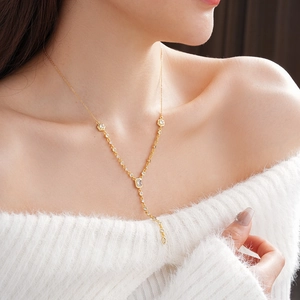 Detail of gold-plated Y-necklace with oval zircon pendant worn by a female model