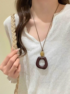 Detail of amber bead and brown resin square pendant on a minimalist waxed cord necklace