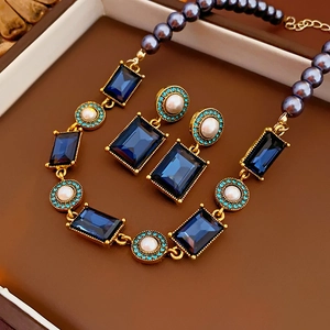 Macro shot of vintage pearl necklace with square blue gemstone and matching earrings