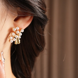 Close-up of vintage flower pearl stud earrings in gold finish on a model's ear