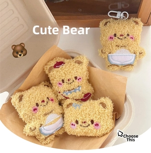 Detail of four cute beige plush bear charms with embroidered faces and metal D-rings