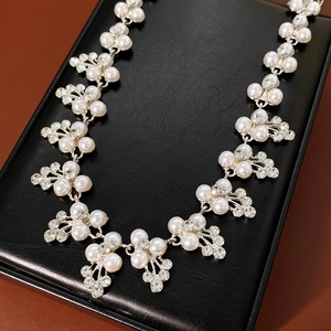 Détail du parure de mariée argentée avec perles blanches et strass brillants sur écrin