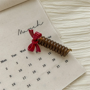Detail of a brown spiral hair tie with a red bow and France handmade tag label