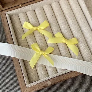 Three bright yellow satin bow hair clips displayed in a vintage wooden jewelry box