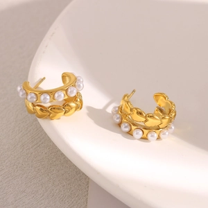 Dettaglio orecchini a cuore in oro 18K con perle finte bianche su piatto ceramica