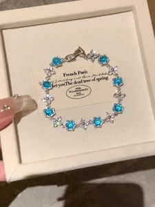 Detailed close-up of a silver flower bracelet with blue stones in a velvet box