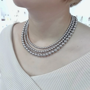 Close-up of triple-layered polished silver bead necklace worn by a female model