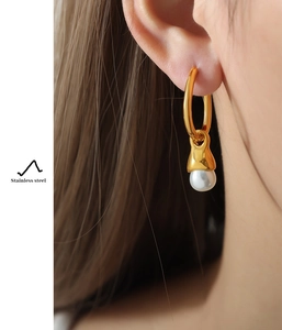 Detail of gold-plated stainless steel earrings with white pearl on a female model