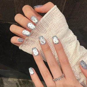 Short square press-on nails with silver glitter and blue polka dots on hands