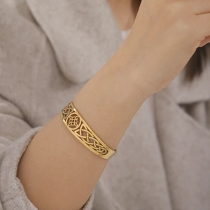 Detailed view of golden stainless steel open cuff featuring intricate Celtic knot cutouts