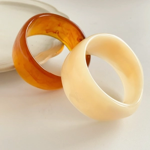 Detail of resin geometric wide bangles in amber and cream ivory marble finish