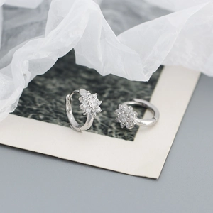 Macro shot of silver plum blossom earrings with crystals on vintage paper background