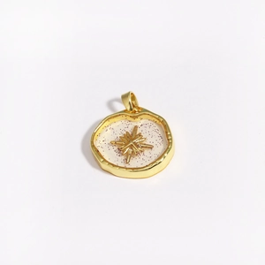 Detail of a gold star and moon pendant with purple glitter on a white background