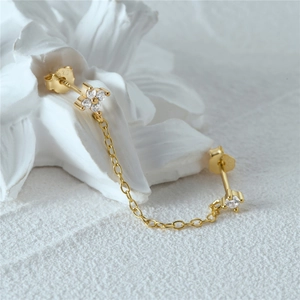 Macro shot of S925 sterling silver gold-plated chain earrings with diamond-set flower
