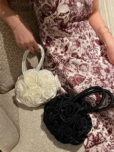 Detailed view of handmade 3D silk rose petals on cream and black evening handbags