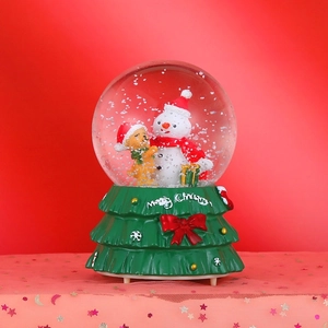 Close-up of a Christmas snow globe music box with snowman, puppy, and Merry Christmas base