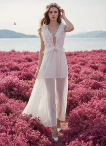 Detail eines eleganten weißen Maxikleides mit tiefem V-Ausschnitt, Rüschen und Spitze