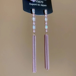Detail of long fringe earrings featuring light purple zircons and metallic mesh tassels