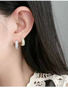 Detail of square zircon row inlay on silver and gold plated C-shaped hoop earrings