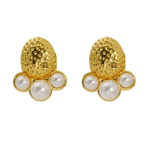 Detailed view of gold plated hammer-textured metal earrings with inlaid white pearls
