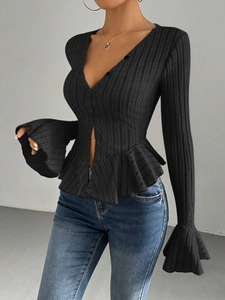 Detail of black V-neck knitted top with ribbed texture and ruffled hem and cuffs