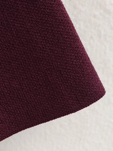 Detailaufnahme der hochwertigen tiefburgunderroten Strickstruktur mit feiner Webart