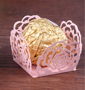 Close-up of pink laser-cut rose hollow favor box with a gold foil chocolate inside