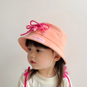 Detail of coral orange kids bucket hat with pink decorative knot and piece out embroidery
