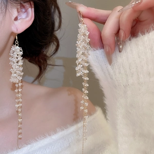Close-up of elegant gold tassel earrings with crystal beads worn on a fuzzy sweater